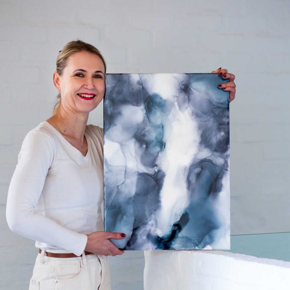 Woman holding a large abstract painting with a gray background